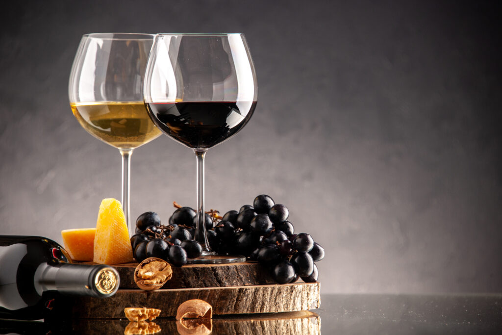 front-view-wine-glasses-fresh-grapes-walnuts-yellow-cheese-wood-board-overturned-bottle-dark-background-1024x683.jpg