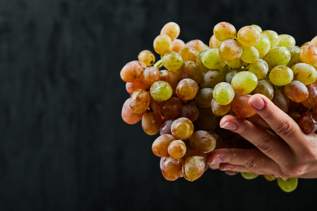 bunch-fresh-grapes-hand-black-surface-1024x683.jpg